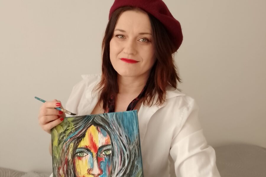 Joanna Bogusz-Paszek z namalowanym przez siebie obrazem, abstrakcyjnym portretem kobiety.