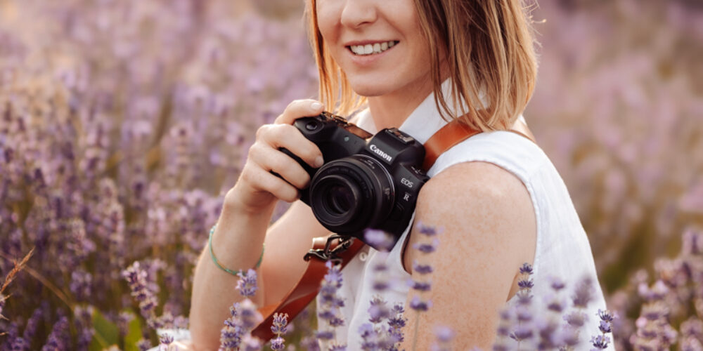 Alina Niewiadomska z aparatem fotograficznym wśród wrzosów.