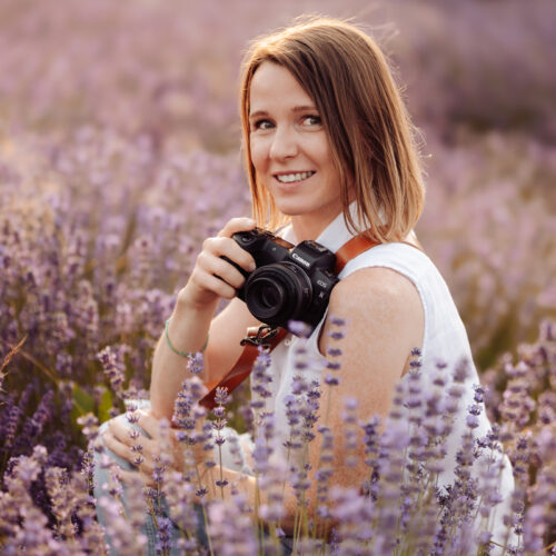 Alina Niewiadomska z aparatem fotograficznym wśród wrzosów.