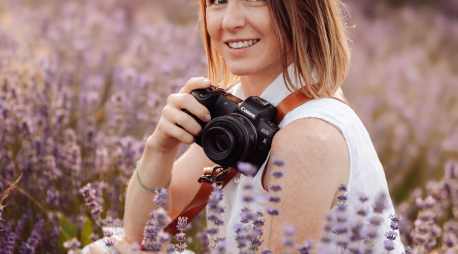 Alina Niewiadomska z aparatem fotograficznym wśród wrzosów.