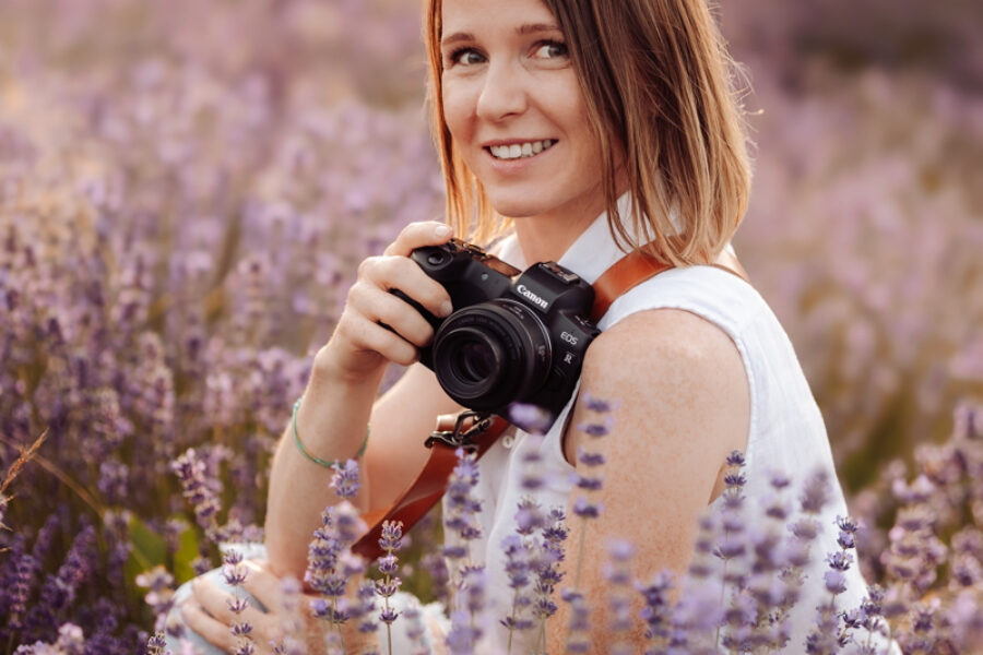 Alina Niewiadomska z aparatem fotograficznym wśród wrzosów.