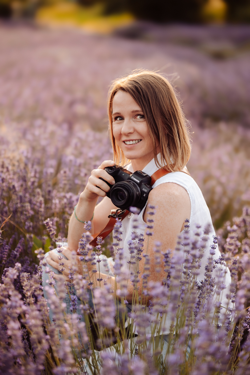 Alina Niewiadomska z aparatem fotograficznym wśród wrzosów.